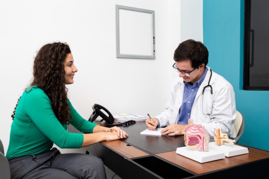female patient in green top getting consultation for crohn's disease with doctor